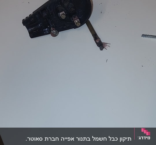 חלק חשמלי שבור עם חוטים חשופים על שולחן